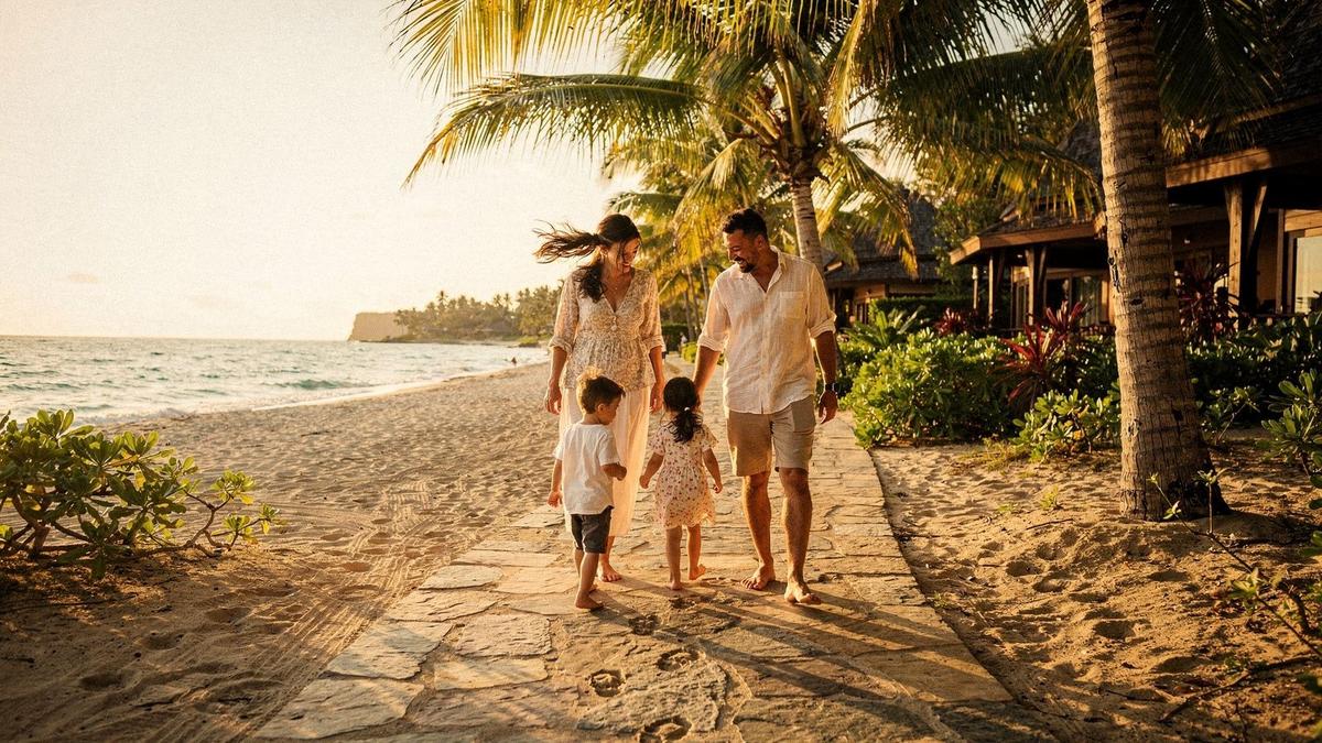 Parents and two children walking a resort beach path at sunset